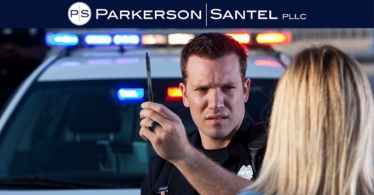 Police officer conducting horizontal gaze nystagmus test on woman with car in the background