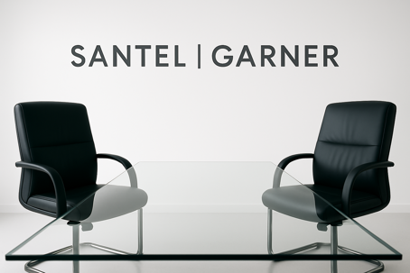 A modern, minimalist conference room with a glass-top table and two black leather chairs facing each other. The firm name "SANTEL | GARNER" is displayed in bold, dark letters on a clean white wall in the background.